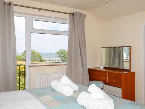 a bedroom with a bed with a view of the ocean at Hafan Deg in Pwllheli