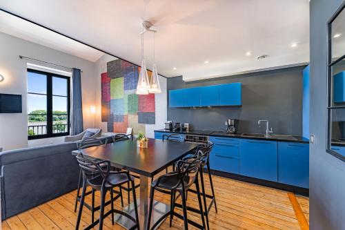 une cuisine et une salle à manger avec des armoires bleues et une table dans l'établissement Appartement Climatisé 3 Chambres Vue Garonne, à Bordeaux