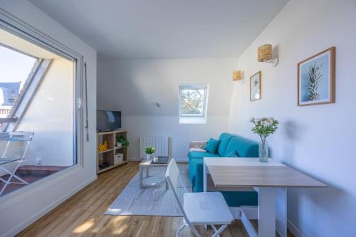 un salon avec un canapé bleu et une table dans l'établissement Duplex Les Mouettes - Welkeys, à Cabourg