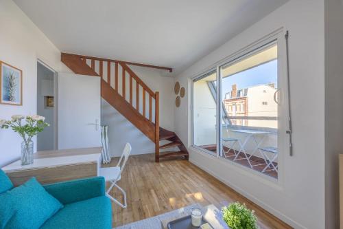un salon avec un canapé bleu et une grande fenêtre dans l'établissement Duplex Les Mouettes - Welkeys, à Cabourg