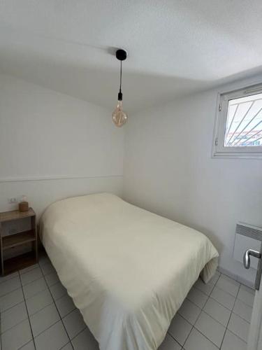 une chambre blanche avec un lit et une fenêtre dans l'établissement T2 au cœur de la Marina, à Sète