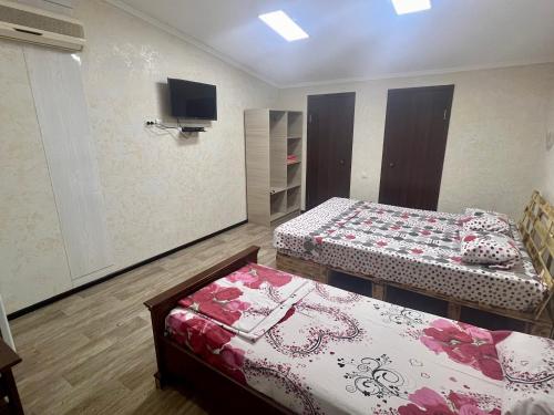 a room with two beds and a tv on the wall at Гостевой дом Сафар in Kapchagay