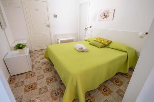 a bedroom with a green bed with two pillows on it at Le Torrette Rooms and Apartments in Avola