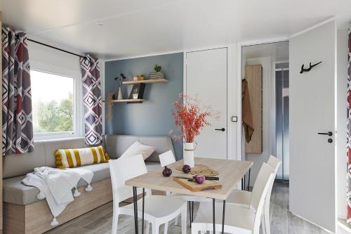 une salle à manger et un salon avec une table et des chaises dans l'établissement Mobil home - Domaine du Vieux Moulin, à Saint-Julien-en-Born