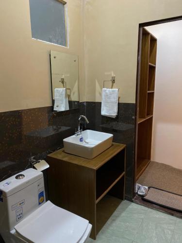 ein Badezimmer mit weißer Toilette und Waschbecken in der Unterkunft Rangjon Resort in Meruk