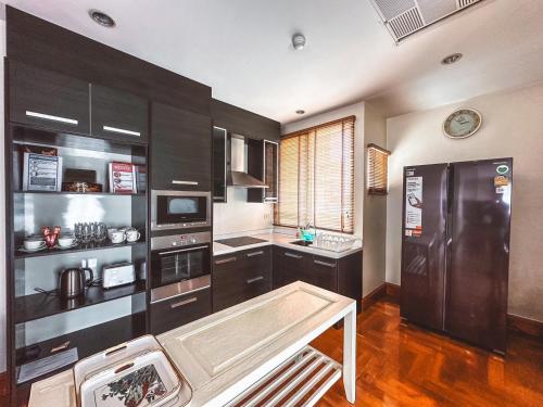 a kitchen with black cabinets and a black refrigerator at Chez Moi Bangkok Private Executive Residence Sukhumvit 26 in Khlong Toei
