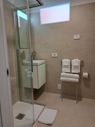 a bathroom with a shower and a sink and towels at Villa Miryam in Ponte di Legno