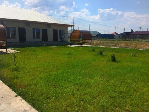 a yard with a building and a grassy yard with benches at Акватель Aquatel in Akshi