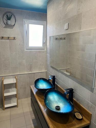 une salle de bains avec deux lavabos bleus sur un comptoir dans l'établissement Le nid douillet classé 2 étoiles, à Ploubazlanec