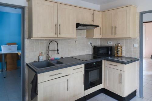 eine Küche mit weißen Schränken und einem schwarzen Waschbecken in der Unterkunft Vacances entre mer et montagne in Alès