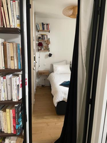- une chambre avec un lit et une étagère avec des livres dans l'établissement Deux pièces lumineux calme, vue sur le ciel !, à Paris