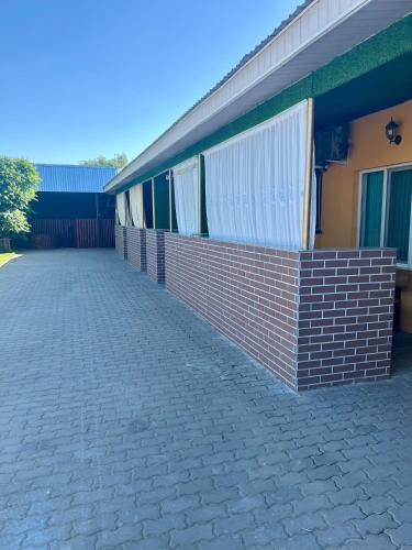 a brick wall next to a building at Гостевой дом Сафар in Kapchagay