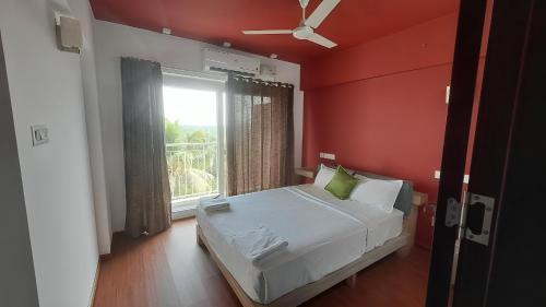 - une chambre avec des murs rouges et un lit avec une fenêtre dans l'établissement GDC - Apartment suites, à Ernakulam