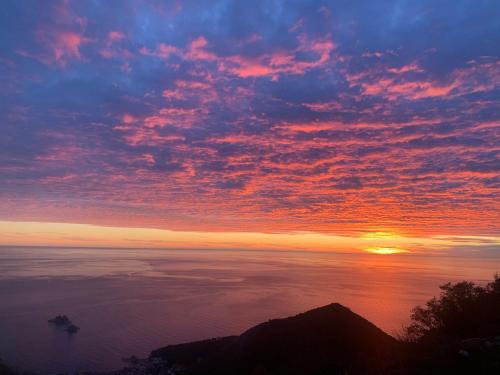 a sunset over the ocean with a boat in the water at Hill Homes Montenegro in Petrovac na Moru