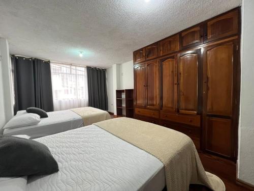 a bedroom with two beds and a large wooden cabinet at Apartment in the city - 2 Bedrooms 2 Bath in Baños