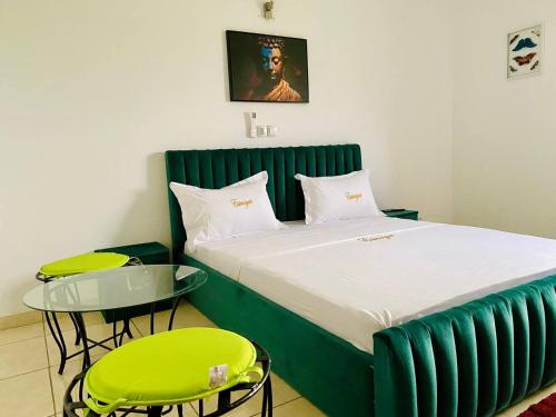 a bed in a room with two chairs and a table at Hotel Résidence Essiéniguet in Abidjan