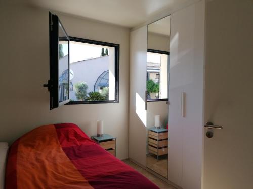 une chambre avec un lit, une fenêtre et un miroir dans l'établissement A GAUGUIN Cyclistes Ventoux, à Malaucène