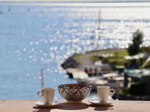 two cups on a table with a view of the water at Portopiccolo Apartments in Sistiana