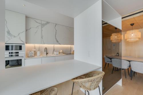 a kitchen with white cabinets and a table and chairs at Chic Two-Bedroom En Suite in Central Town - Savoy Residence in Funchal