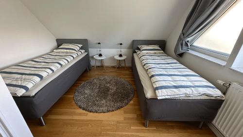 two beds in a small room with a rug at Cozy Villa apartment in Malmö