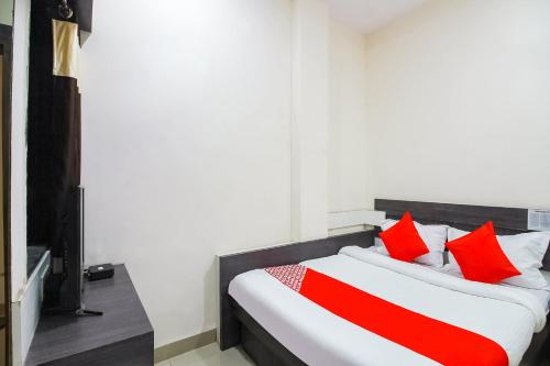 a bedroom with a bed with red pillows at Hotel O Unique Inn in Dhule