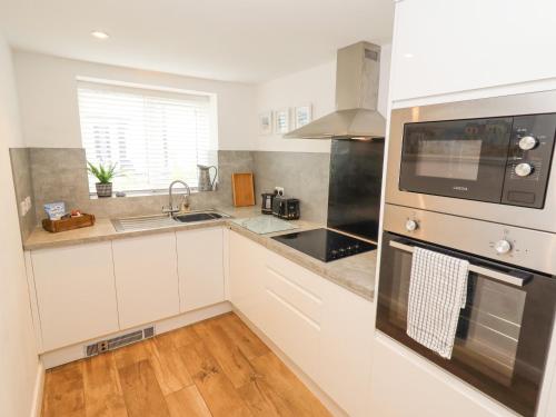 a kitchen with white cabinets and a sink and a microwave at Sea View Terrace in Conwy