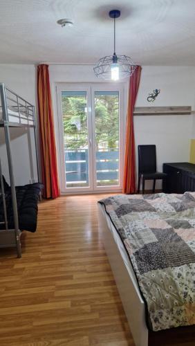 a bedroom with a bed and two windows and a balcony at Zweizimmerwohnung - Ferienwohnung im Sankt Englmar in Sankt Englmar