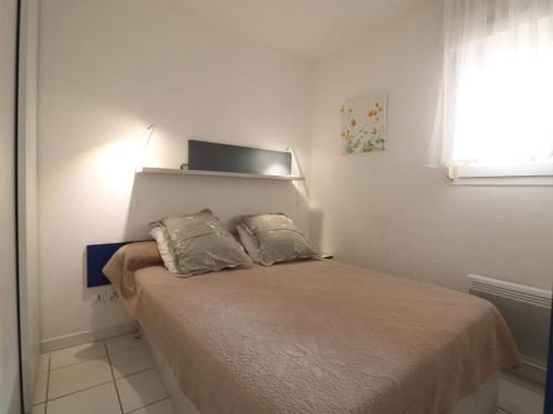 une chambre avec un lit avec deux oreillers dessus dans l'établissement Charmant T2 avec loggia, wifi, parking, proche plage - FR-1-472A-197, à Sète