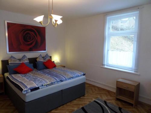 a bedroom with a bed with red pillows and a window at Bürgermeisterwohnung Altesrathaus in Wildemann