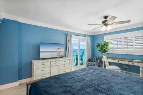 a bedroom with blue walls and a bed with a television at 4 Loungers 2 Umbrellas Inlc Peak Season Beachfront in Panama City Beach