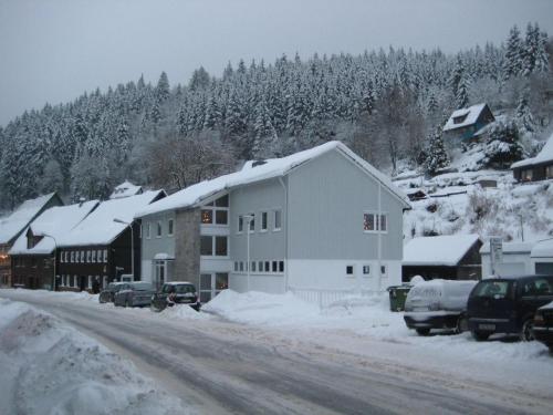 a building on a snow covered street with cars parked at Bürgermeisterwohnung Altesrathaus in Wildemann