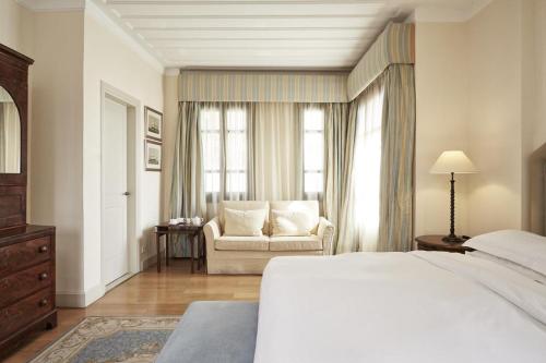 a bedroom with a bed and a couch and a window at The Captain's House Boutique Hotel in Preveza
