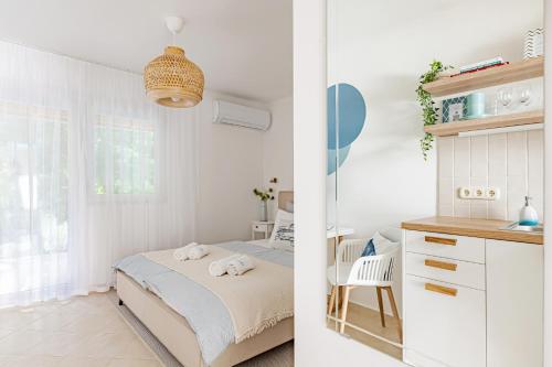 a white bedroom with a bed and a desk at Blue Beach Apartman in Zamárdi