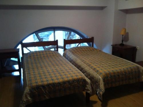 two twin beds in a room with a window at Filoxeno in Ermoupoli