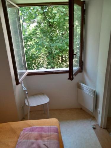 - une chambre dotée d'une fenêtre avec une chaise et un lit dans l'établissement Appartement privatif en bord de rivière, à Figeac