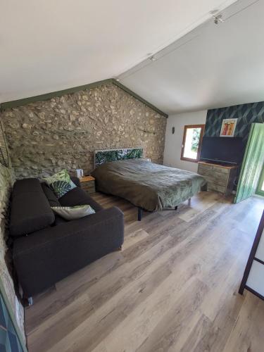 une chambre avec un lit et un canapé dans une pièce dans l'établissement Maison de village en Provence, à Saint-Roman-de-Malegarde
