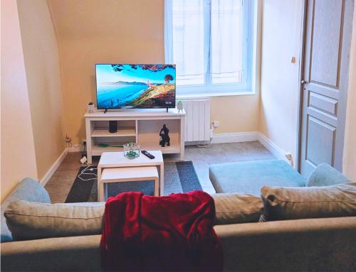 un salon avec un canapé et une télévision à écran plat dans l'établissement Le Mahanaim House, à Nevers