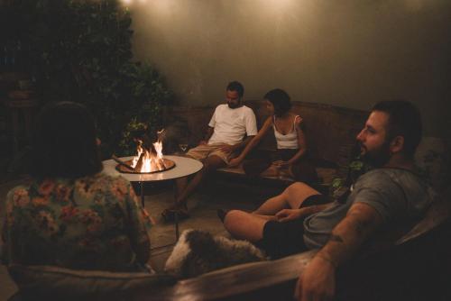 a group of people sitting on a couch around a fire at Villabuca in Ubatuba