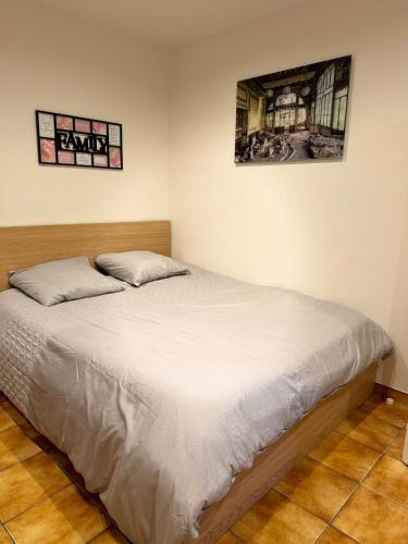 un lit dans une chambre avec deux tableaux au mur dans l'établissement Maison proche Paris métro 13, à Pierrefitte-sur-Seine