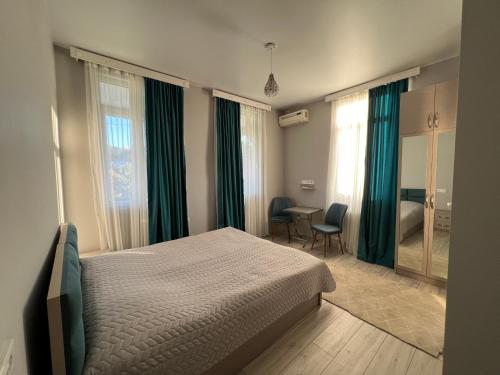 a bedroom with a bed and green curtains and a desk at Семейная гостиница Гантиади in Batumi