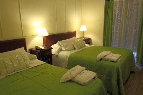 two beds in a hotel room with green sheets at Hotel Plaza Roma in Buenos Aires