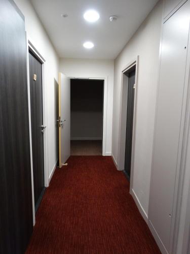 a hallway with two doors and a red carpet at Hotel Restaurant L Echo du Lac in Gérardmer