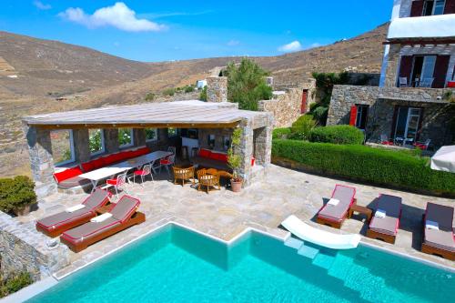 a house with a pool with chairs and a gazebo at VILLA NAUTILIA - Luxury Suites and Cottages in Kalafatis