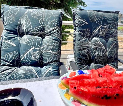 a table with a bowl of watermelon and a plate of fruit at Nikiti Sunny House in Skála Nikíta