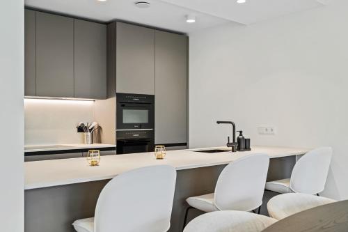 a kitchen with white appliances and white stools at Spacious 6th-Floor Gem: Modernity Meets Comfort in Luxembourg