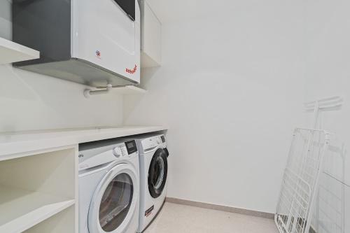 a washer and dryer in a white laundry room at Spacious 6th-Floor Gem: Modernity Meets Comfort in Luxembourg