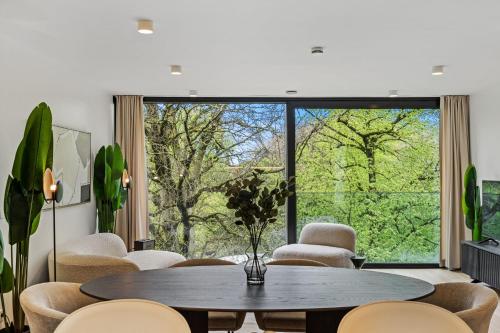 a living room with a table and chairs and a large window at Spacious 6th-Floor Gem: Modernity Meets Comfort in Luxembourg