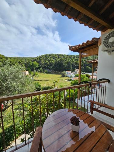 a wooden table on a balcony with a view of a field at The Pine Trees in Agnontas
