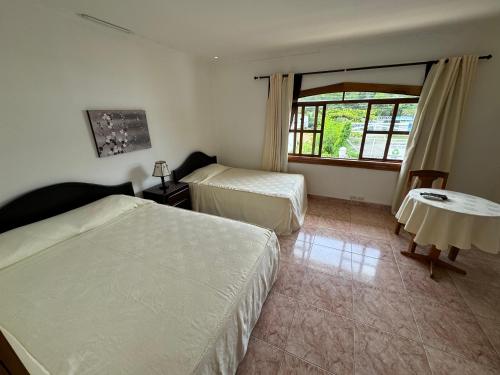 a bedroom with two beds and a table and a window at Hotel y Restaurante Costa del Sol in Mata de Limón