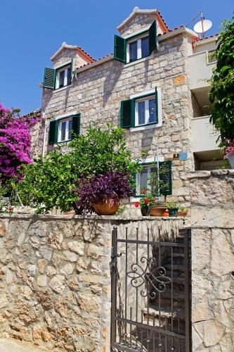 a stone building with potted plants and a gate at Apartment Vanja in Bol